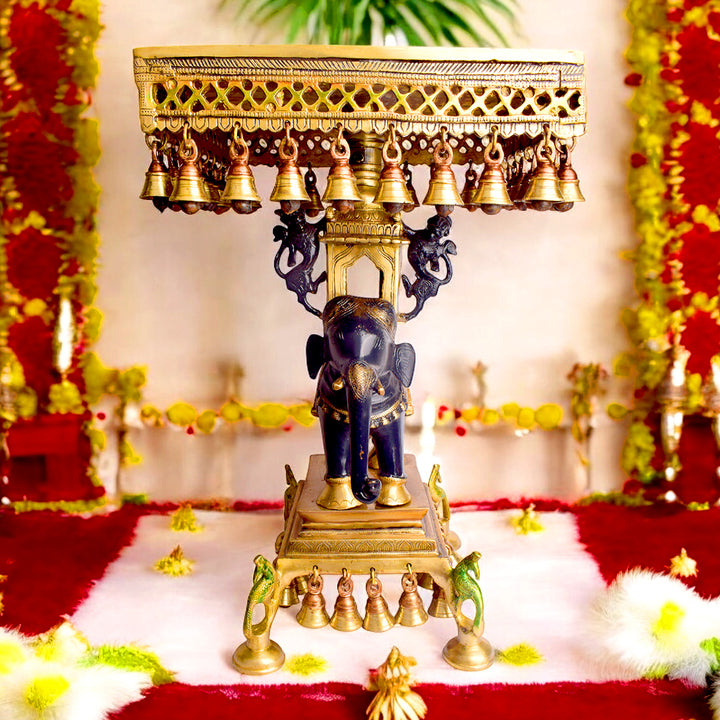 Large Brass Idol of 23 Inch Brass Chowki on Elephant with Hanging Bells. This 23 Inch Brass Chowki on Elephant with Hanging Bells is a stunning blend of artistry and tradition. Crafted from high-quality brass, the intricate detailing of the elephant and the delicately suspended bells add a touch of elegance to any space.