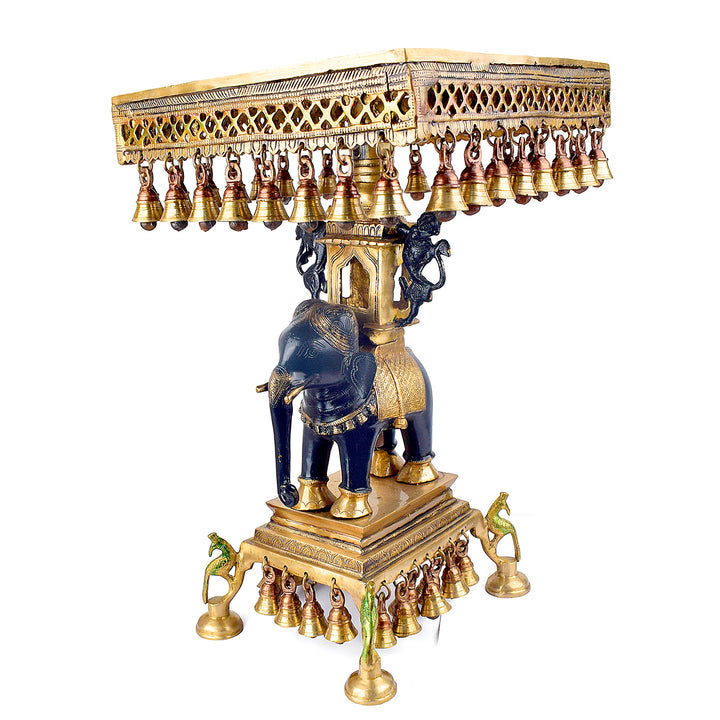 Large Brass Idol of 23 Inch Brass Chowki on Elephant with Hanging Bells. This 23 Inch Brass Chowki on Elephant with Hanging Bells is a stunning blend of artistry and tradition. Crafted from high-quality brass, the intricate detailing of the elephant and the delicately suspended bells add a touch of elegance to any space.